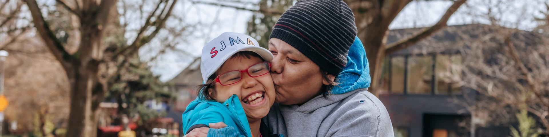 Mother kisses daughter on the cheek