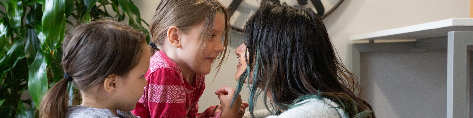 Mother and daughters looking at each other in the eyes, smiling