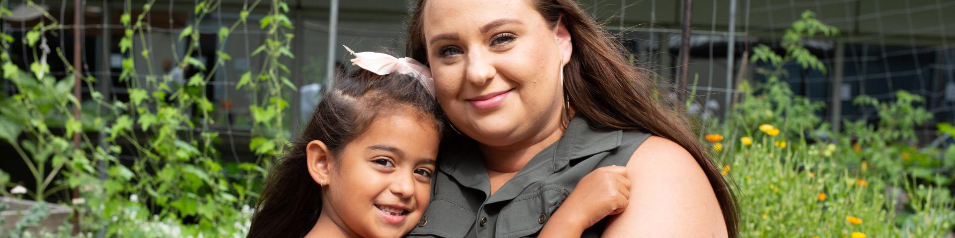 Mom and daughter hugging outside 