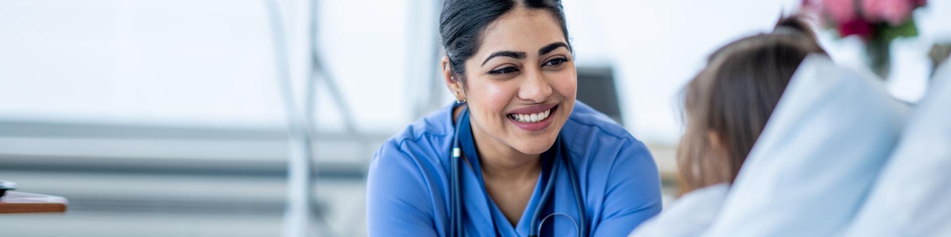 Female nurse in a hospital looking at a patient in bed