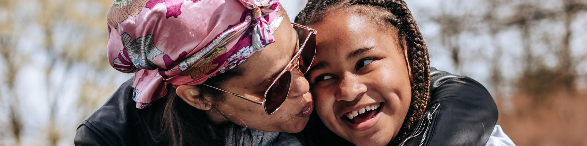 Mother kisses daughter on the cheek