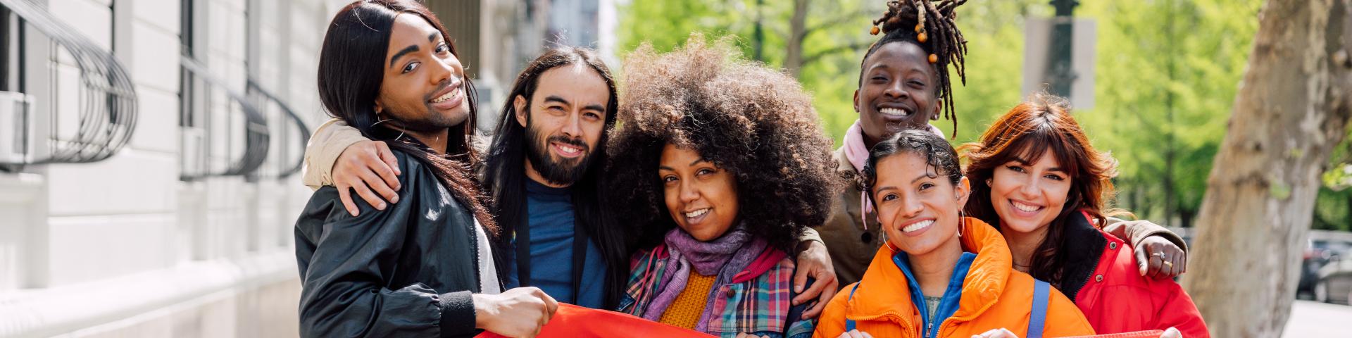 Diverse group of individuals holding a pride flag