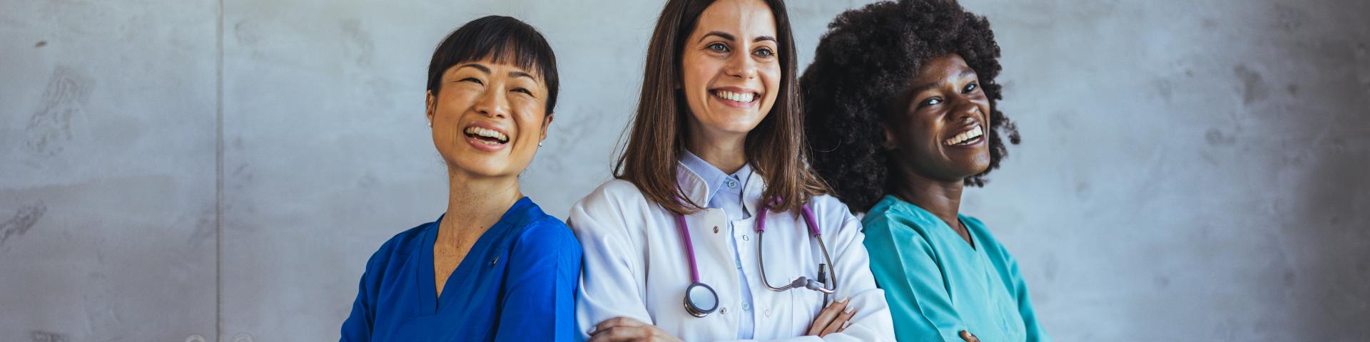 A diverse team of healthcare professionals, including doctors and nurses, smiling confidently in a hospital setting, promoting teamwork and diversity in the medical field.