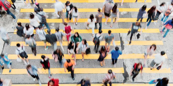 Multiple people crossing a busy city street 