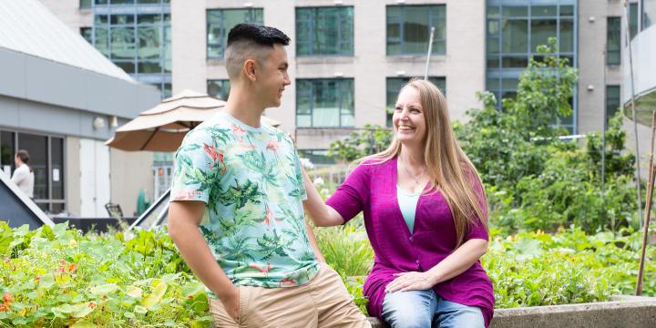 Young man in floral t-shirt and women in solid pink cardigan smiling at each other