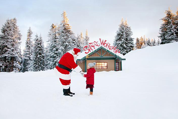 Photo of Santa and child in front of Santa's Workshop at the Peak of Christmas