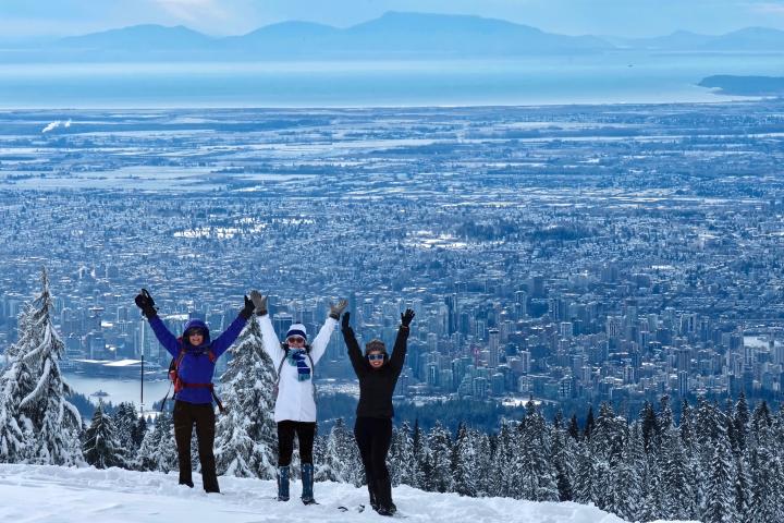 Photo of hikers overlooking the cityscape of Vancouver during a snowy Winter day
