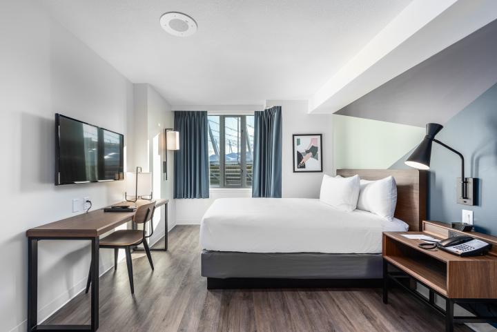 New rooms in YWCA Hotel Vancouver featuring a queen bed, desk, tv and bedside table