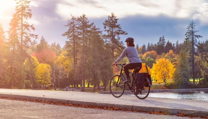 Woman biking along the Stanley Park seawall in the fall