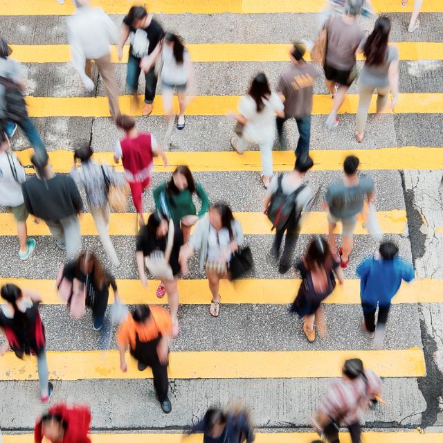 Multiple people crossing a busy city street 