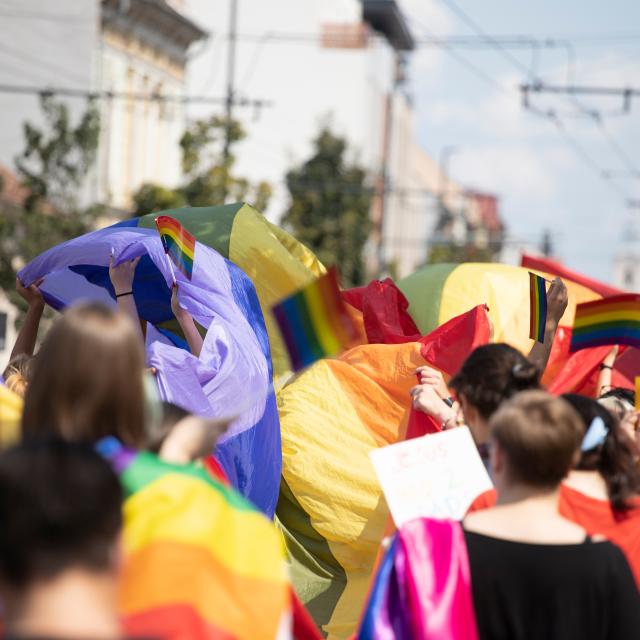A crowd of people dressed in a rainbow of colours walk as part of a PRIDE parade
