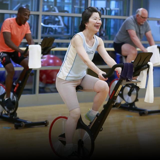 Three people exercising on a spinning bike at the HF Centre