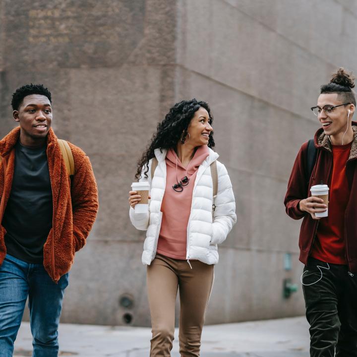 Image of three diverse individuals walking in the city having a conversation